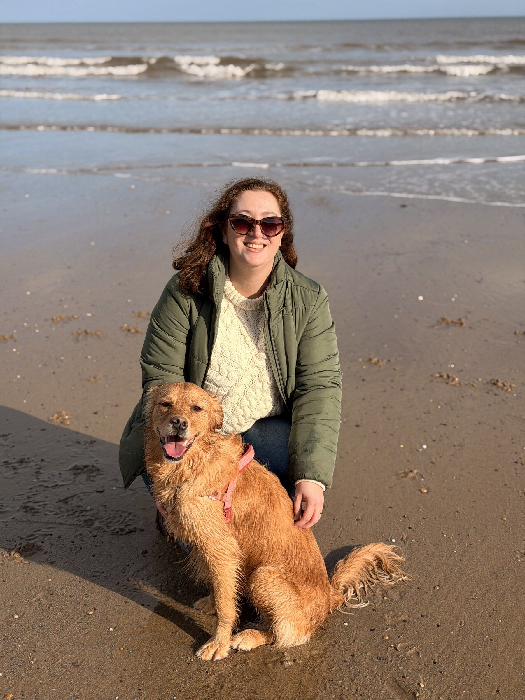 Tamara crouching beside Skye on wet sand, the sea behind them